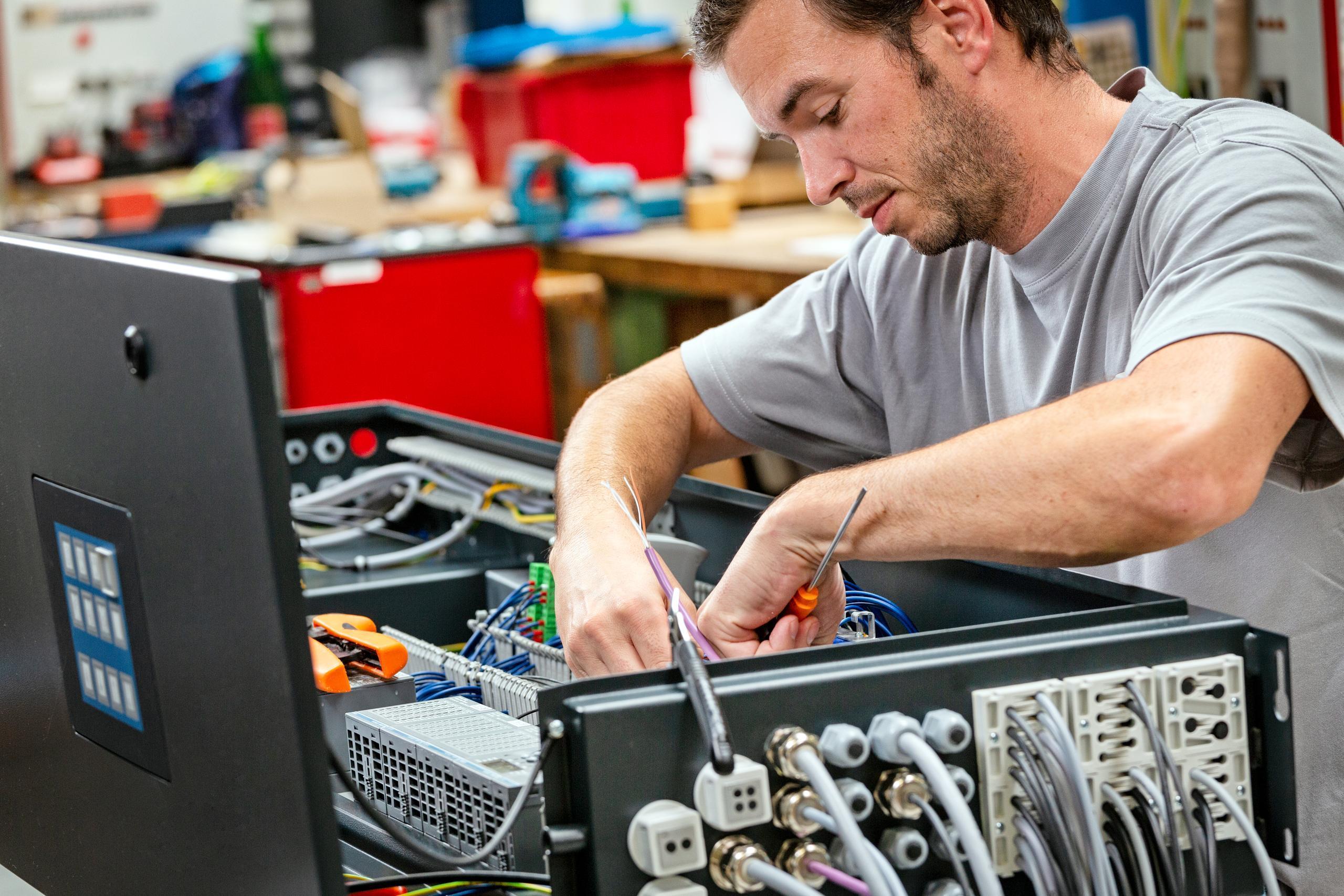 Elektriker im Werk Schaltschrank bauend